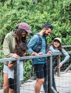 Une famille observe le ruisseau depuis un petit pont en bois sur le sentier du patrimoine à Munacia d’Auddè, en Corse-du-Sud.