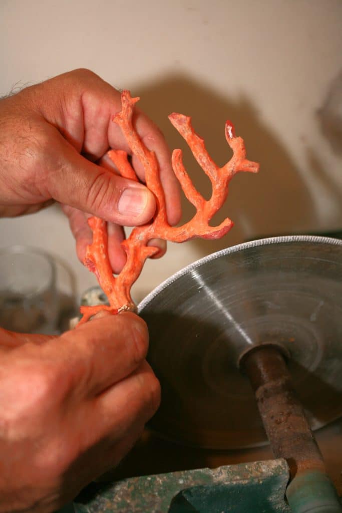 Découpe artisanale d’un morceau de corail au disque dans l’atelier