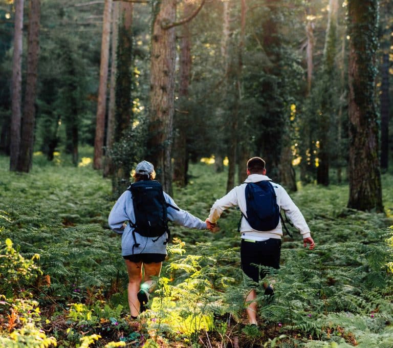 Couple de randonneurs marchant dans la forêt de l’Ospedale entourée de fougères en Corse