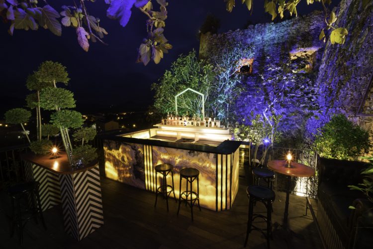 Comptoir extérieur et tables hautes  sur la terrasse panoramique, éclairée de nuit, avec vue sur la baie de Porto Vecchio