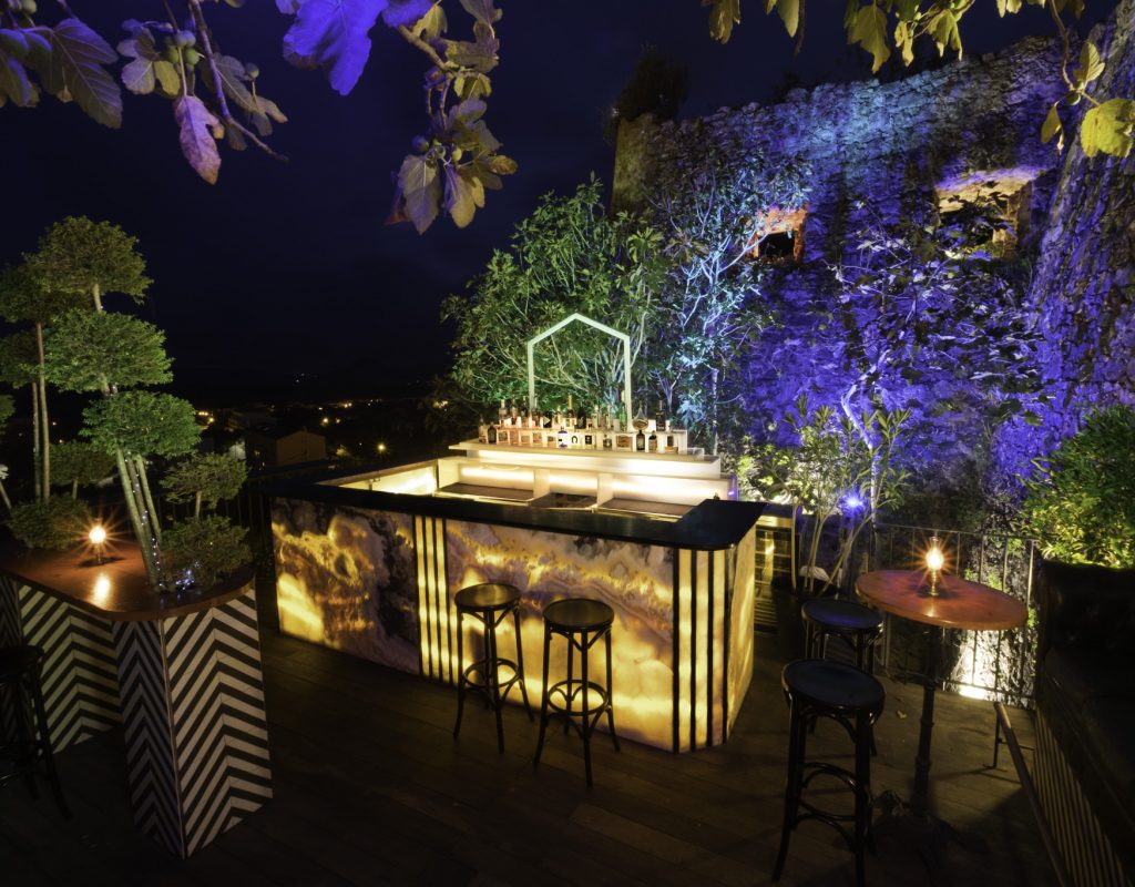 Comptoir extérieur et tables hautes  sur la terrasse panoramique, éclairée de nuit, avec vue sur la baie de Porto Vecchio