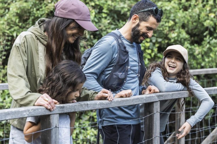 Famille en randonnée sur un pont en bois du sentier du patrimoine à Monacia d'Aullène, Corse.