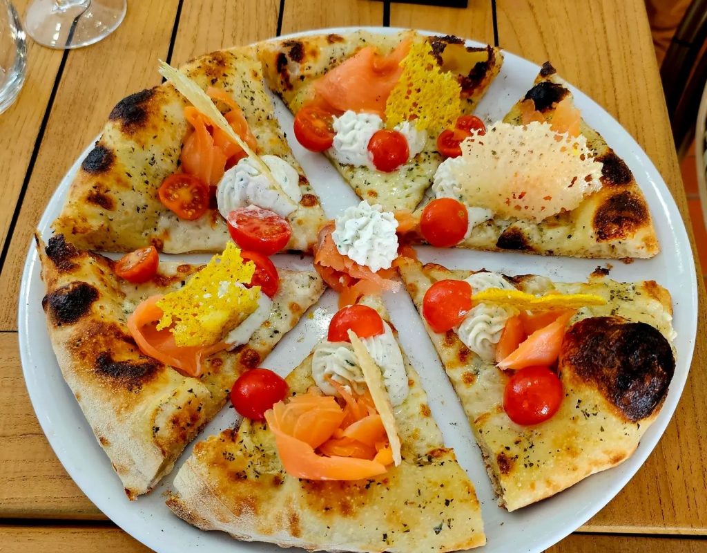 Pizza à partager garnie de saumon fumé, tomates cerises,  crème et chips de fromage