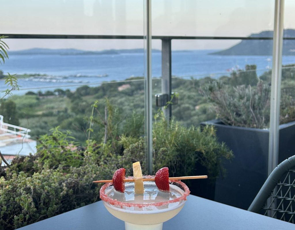 Cocktail avec brochette de fruits, en coin de terrasse vitrée intérieure, et golfe de Porto Vecchio
