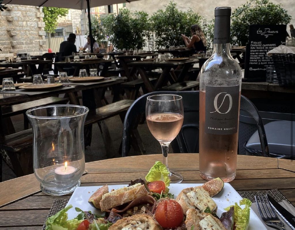 Assiette avec salade, tomates cerises et toasts de fromage servie sur une table de la terrasse ombragée