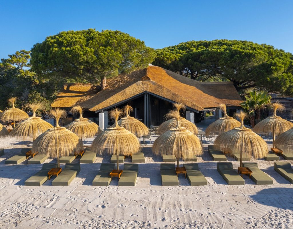 Vue aérienne, de face, de la paillotte avec son restaurant et ses transats et parasols au bord de l'eau