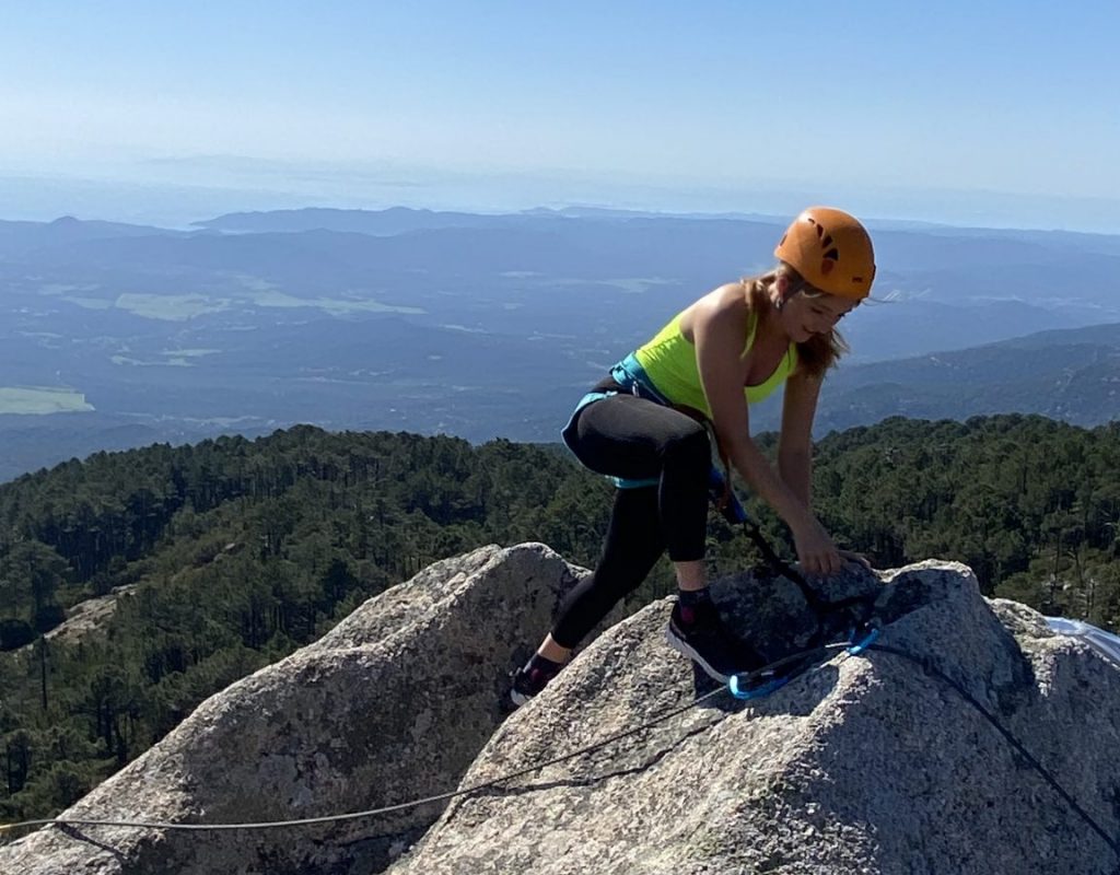 Femme en escalade avec vue panoramique de la foret et côte