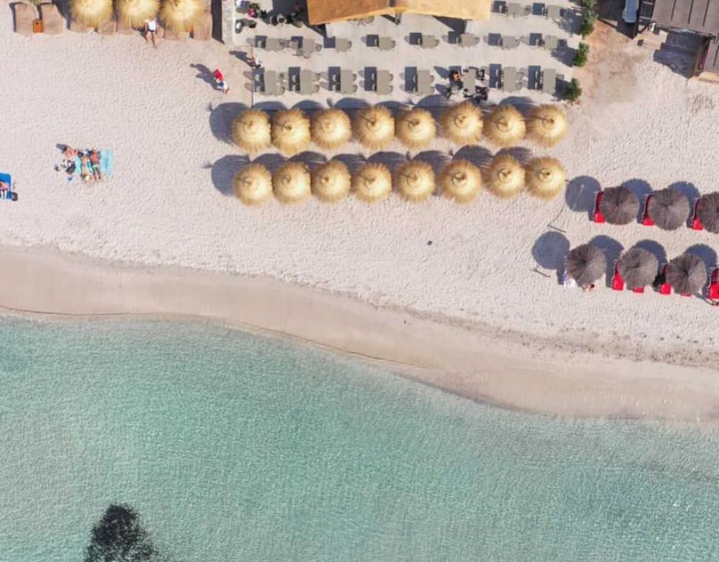 Vue aérienne prise au dessus de la paillotte, avec les tables côté restauration et les parasols au bord de l'eau