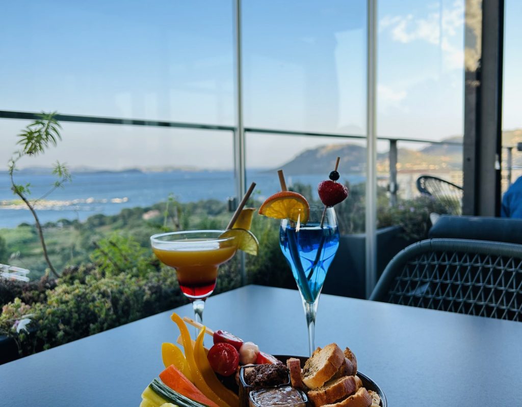 Cocktails accompagnés d'une assiette de tapas et crudités avec le golfe de Porto Vecchio en arrière plan