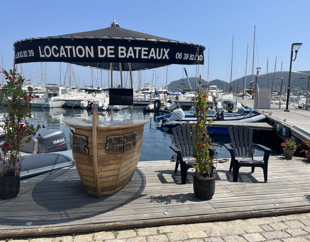 Bureau d'accueil en bois ombragé sous un soleil éclatant sur le port de plaisance de Porto Vecchio