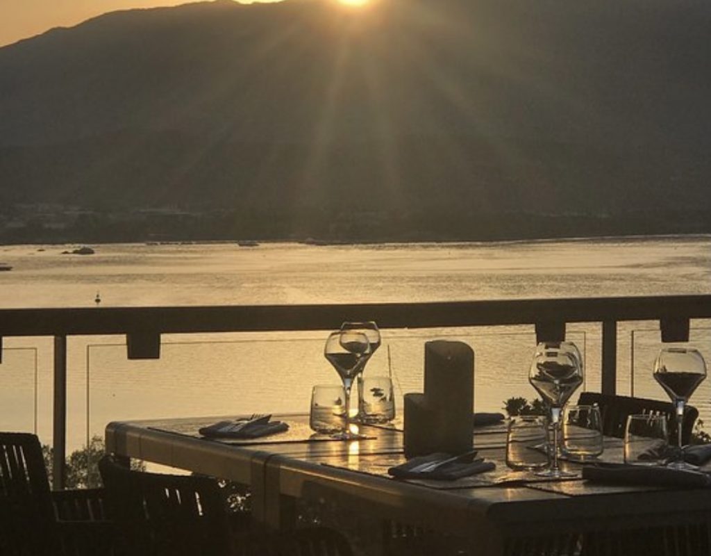 Table dressée pour le dîner au soleil couchant avec le golfe de Porto Vecchio en arrière plan