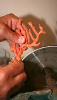 Découpe artisanale d’un morceau de corail au disque dans l’atelier