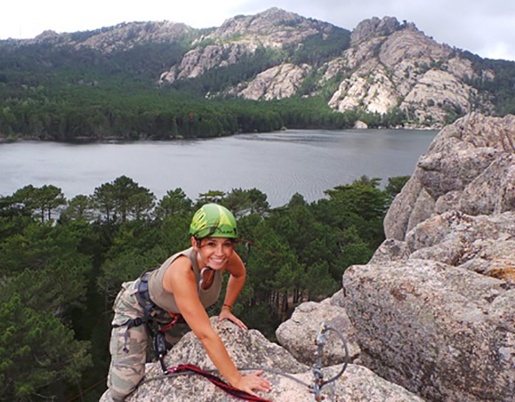 Femme que finit sont escalade, dans le panorama ont peut apercevoir le lac de l'Ospédale entouré de pins